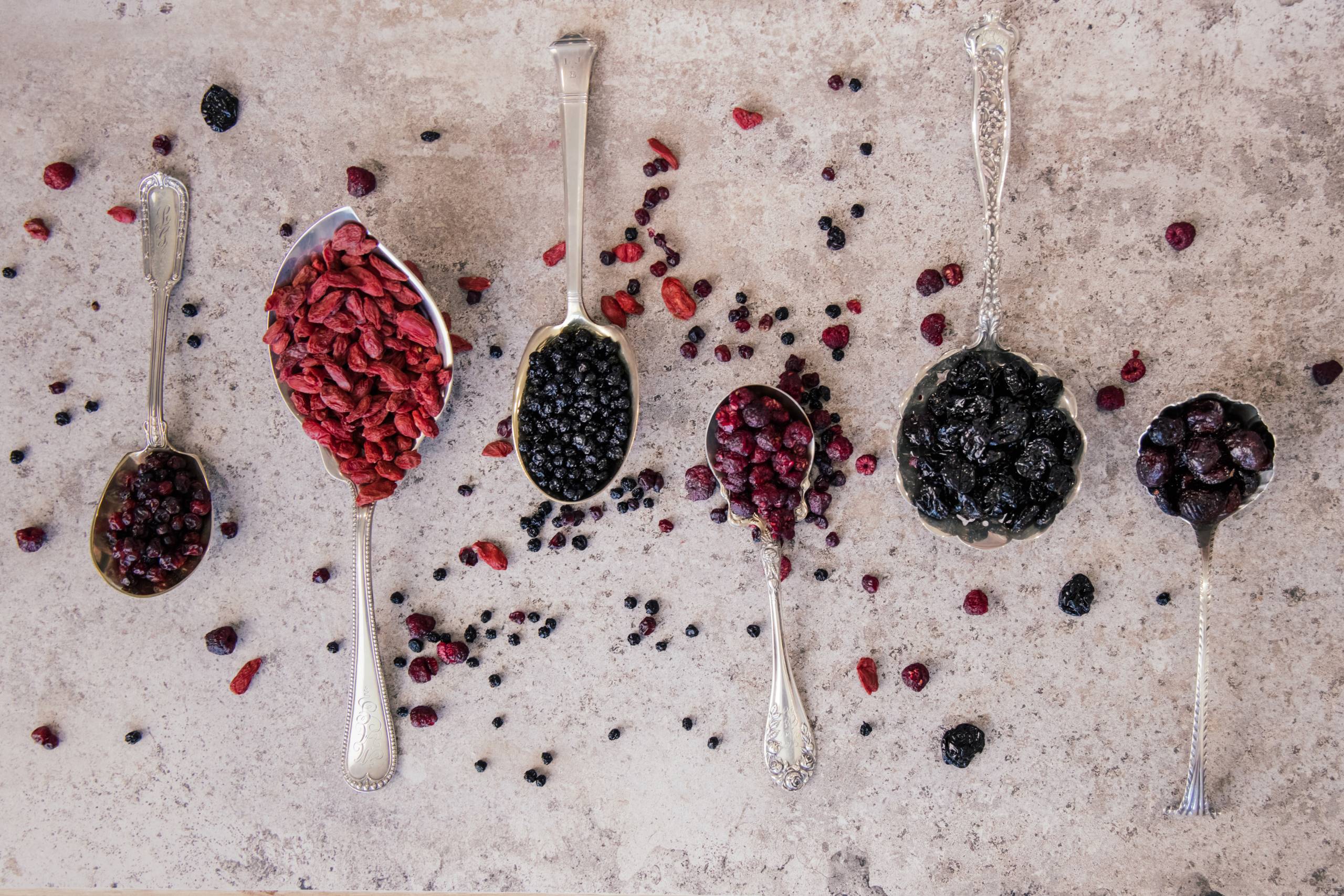 Dried goji berries and mixed superfood berries in antique silver spoons - Dr Superfoods